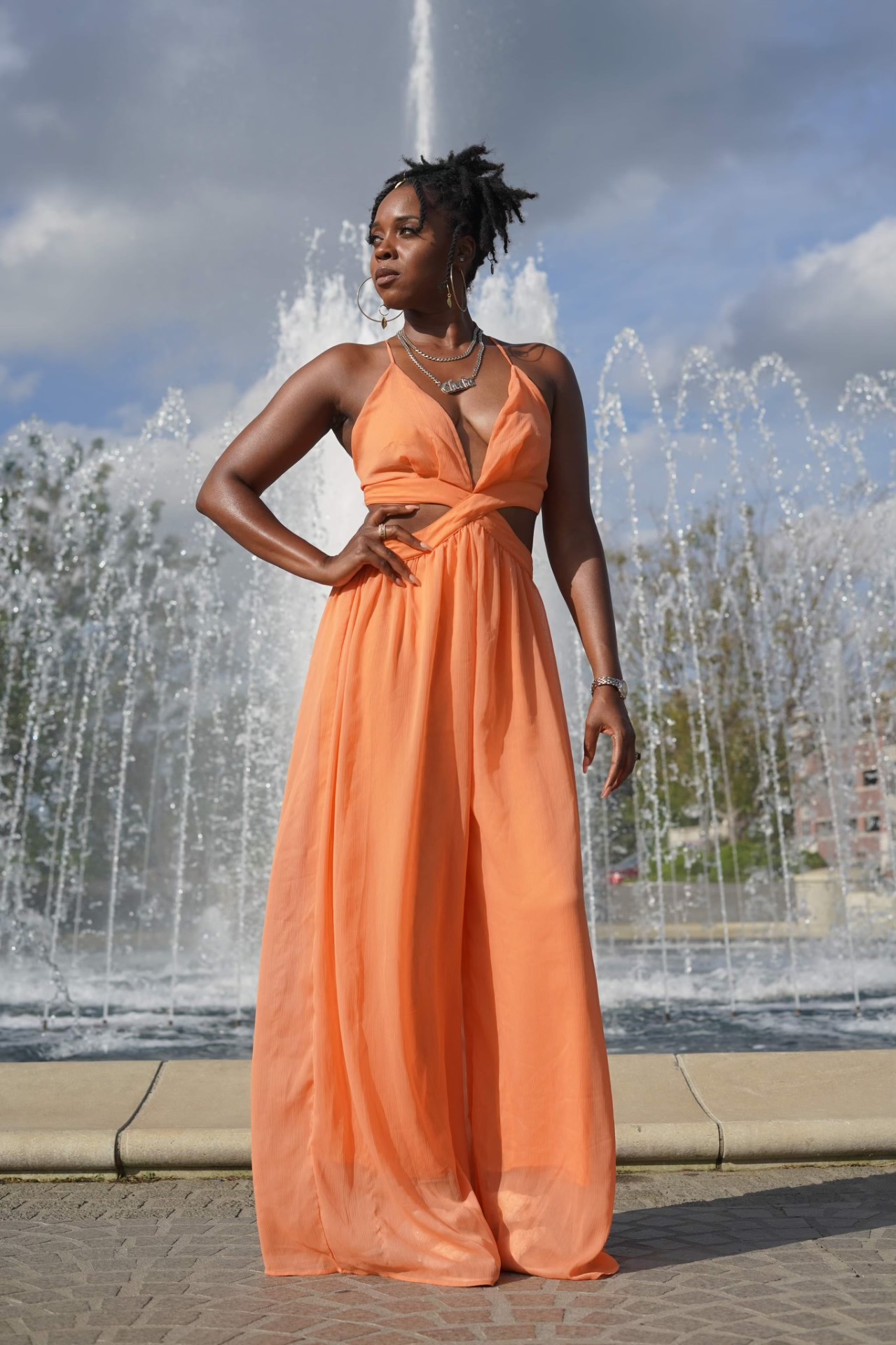 Veronica Washington in a flowing peach gown by a fountain